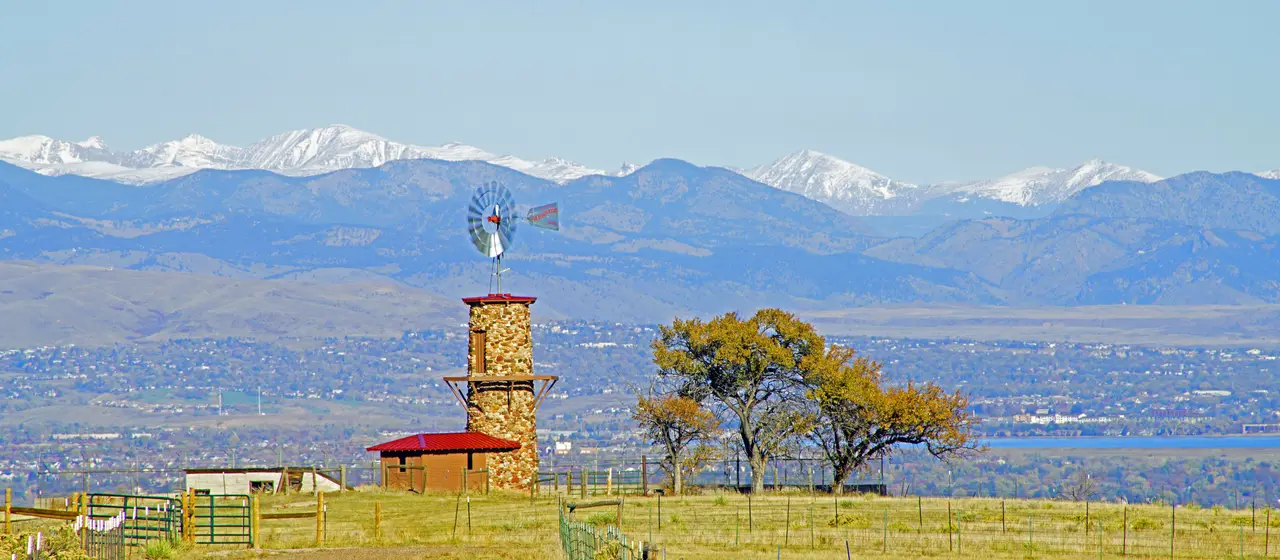 Historic stone windmill tower on Highlands Ranch open space with snow-capped peaks behind