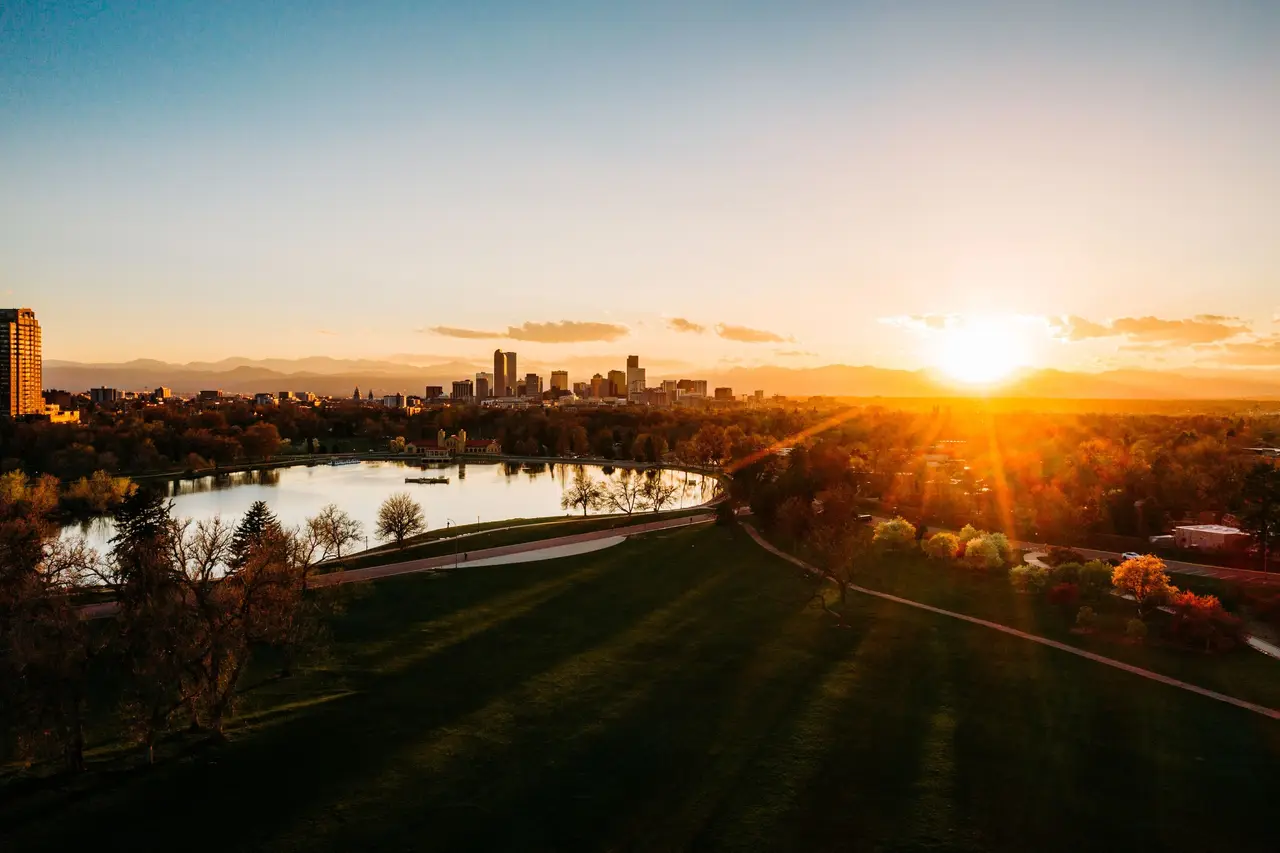 Denver skyline across City Park at sunset, with the Front Range behind